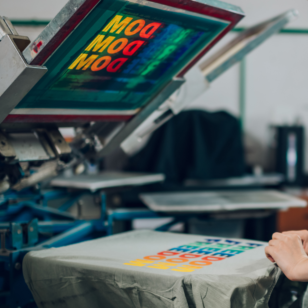 Processo de impressão em Silk Screen (serigrafia) em camisetas. Máquina aplicando tinta colorida diretamente no tecido com alta definição.